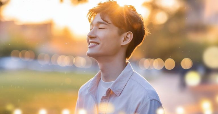 “Young man smiling peacefully in golden sunset light, representing finally being happy and emotional healing”