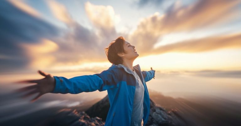 “Person standing on mountain at sunrise symbolizing overcoming struggles and success”